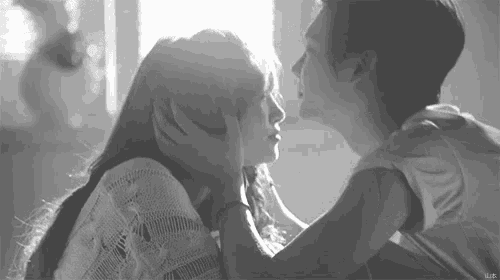 a black and white photo of a man and woman kissing .