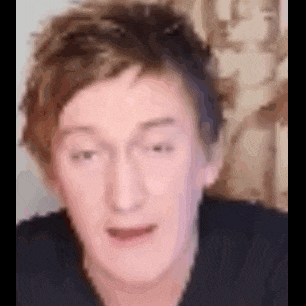 a close up of a man 's face with a blurred background making a funny face .