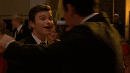two men hugging each other in a room with drums in the background