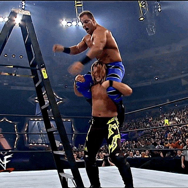 a wrestler is carrying another wrestler up a ladder