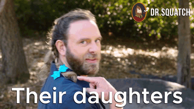 a man with a ponytail is pointing to his daughters