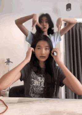 two girls are playing with each other 's hair .