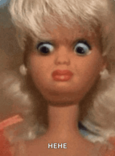 a close up of a barbie doll making a funny face with the words " he he " written below it