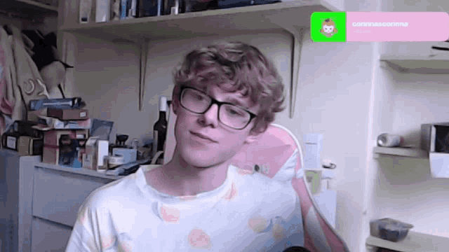 a man wearing glasses is sitting in front of a shelf with a green screen that says correascorima