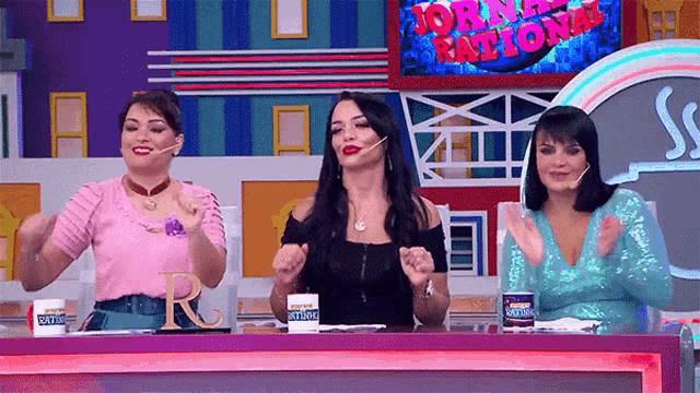 three women sit at a table in front of a sign that says morning national