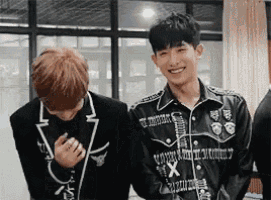 two young men are standing next to each other in a room .
