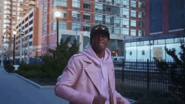 a man wearing a pink jacket and a black hat with the letters x and y on it
