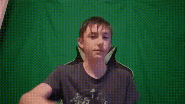 a young man is sitting in front of a green screen and looking at the camera .