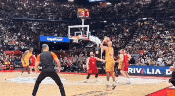 a basketball game is being played in front of a crowd with rivalia advertisements