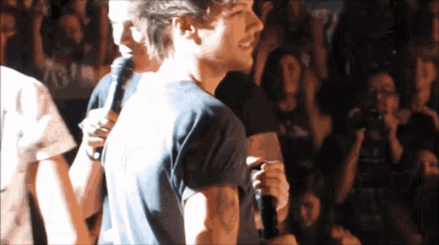a man with a tattoo on his arm holds a microphone in front of a crowd