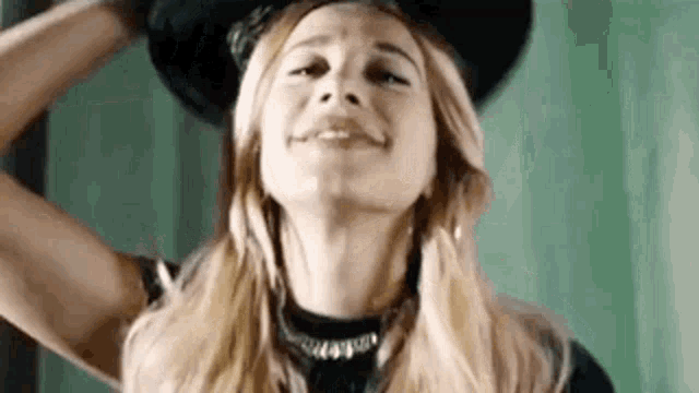a close up of a woman wearing a hat and a choker .
