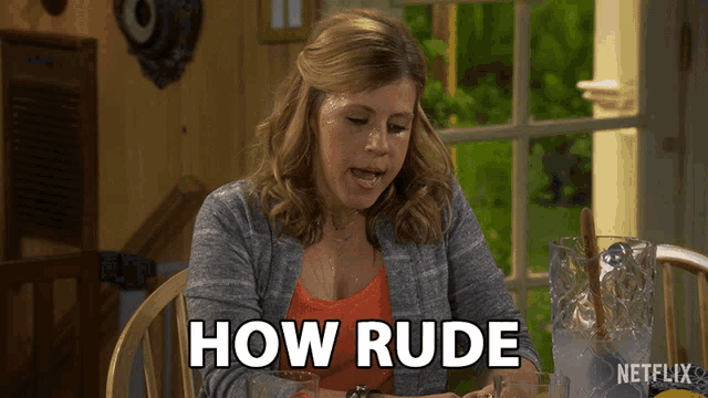a woman sits at a table with a netflix logo on the bottom right