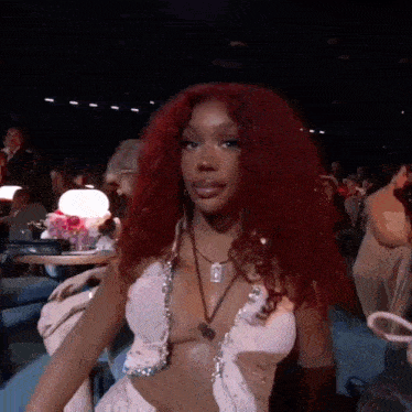 a woman with red hair and a white dress is sitting in a dark room .
