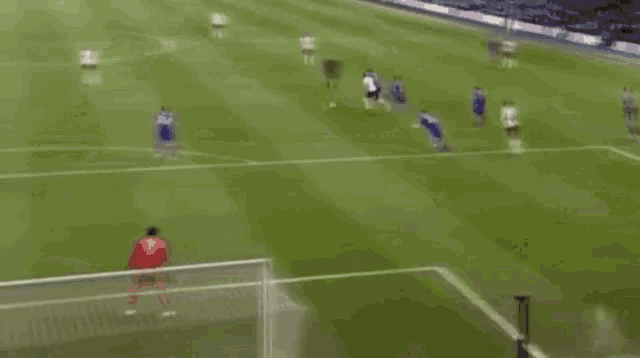 a soccer game is being played on a field and a goalie is diving to save a goal .