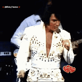 elvis presley is holding a microphone while standing on a stage