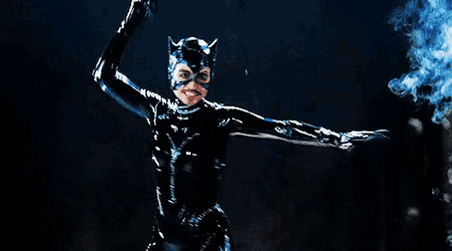 a woman in a catwoman costume is holding a knife in her hand in the dark .