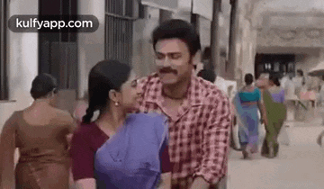 a man is carrying a woman on his shoulders while walking down a street .