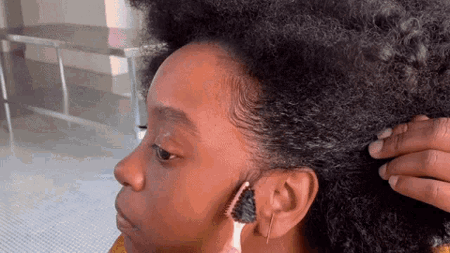 a woman with curly hair is getting her hair done by a person .