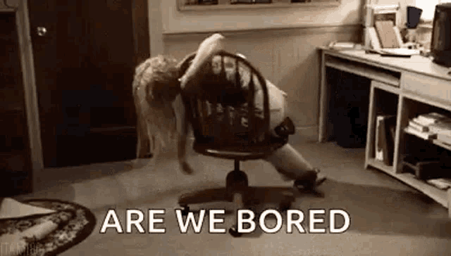 a woman is laying on a chair in an office with the words `` are we bored '' .