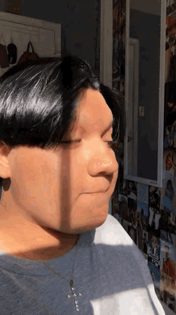 a man with a nose ring is standing in front of a wall with pictures on it