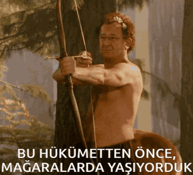 a man without a shirt is holding a bow and arrow in front of a tree with the words bu hukumetten önce