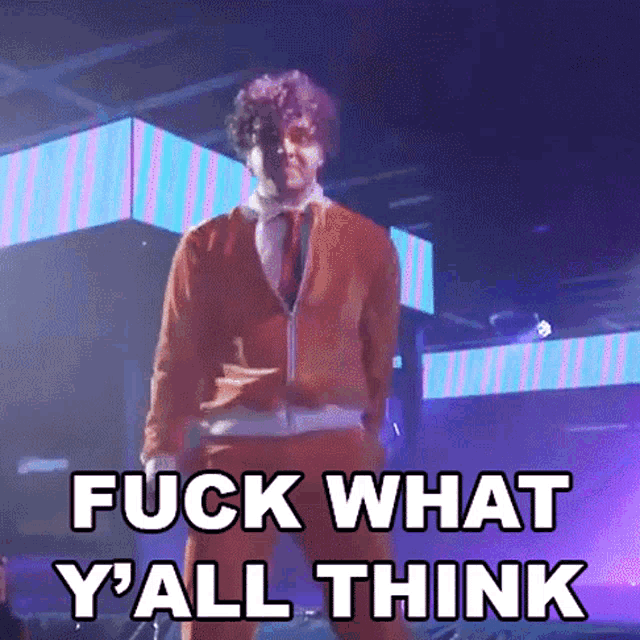 a man is standing on a stage with the words fuck what y all think above him