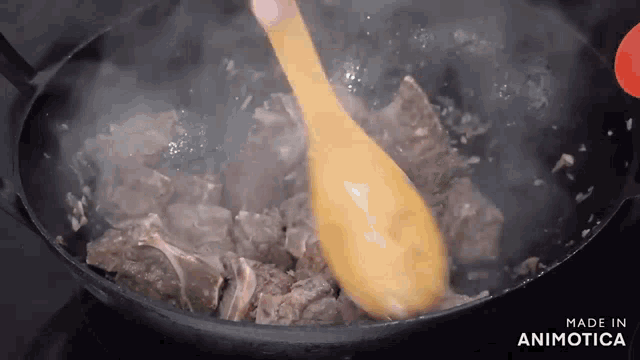 a wooden spoon is being used to stir a pan of meat