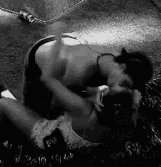 a black and white photo of a man and woman kissing .
