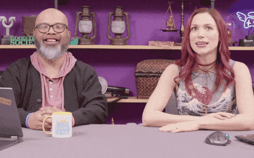 a man and a woman are sitting at a table with a mug that says " small business "