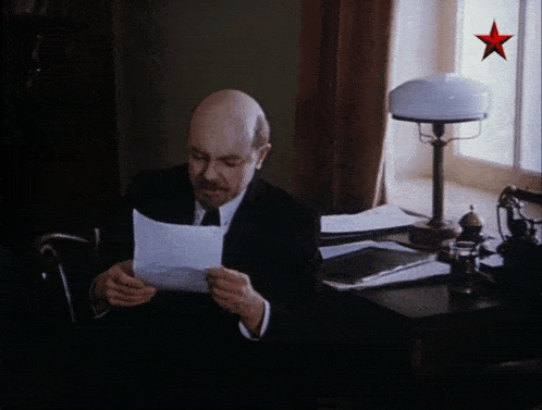 a man is reading a piece of paper with a red star on it