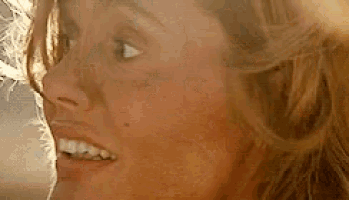 a close up of a woman 's face with a smile on her face and a feather in her hair .
