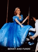 a woman in a blue dress is dancing on a swing with a man in a white suit .
