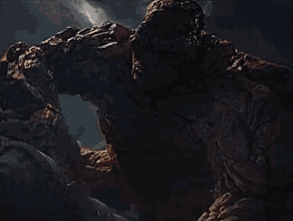 a large rock monster with a huge fist is standing in the dark .