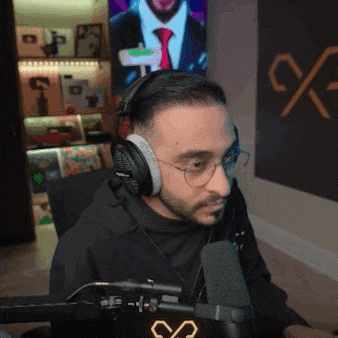 a man wearing headphones and glasses sitting in front of a microphone .