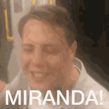 a man is sitting on a bus with his eyes closed and the words `` miranda '' written on the bottom of his face .
