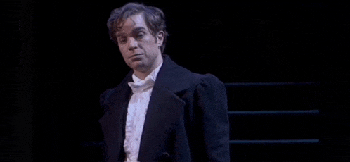 a man in a tuxedo is standing on a stage .