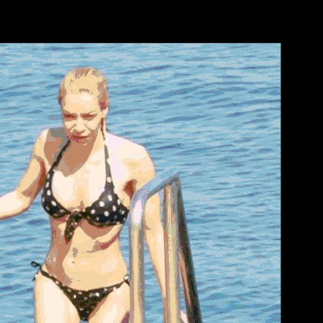 a woman in a black and white polka dot bikini is walking out of the water .
