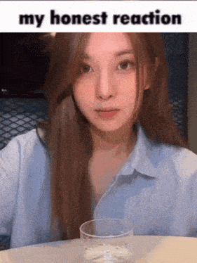 a young woman is sitting at a table with a glass of water .