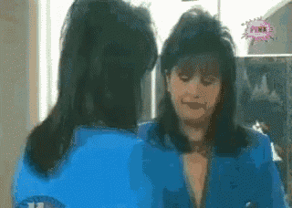 a woman in a blue jacket is looking at herself in a mirror with a pink bubble that says pink