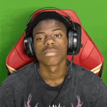 a man wearing headphones is sitting in a chair with a green background