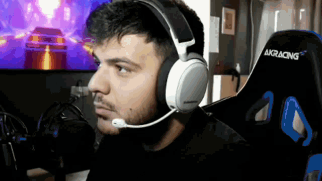 a man wearing headphones and a microphone is sitting in front of a computer screen .