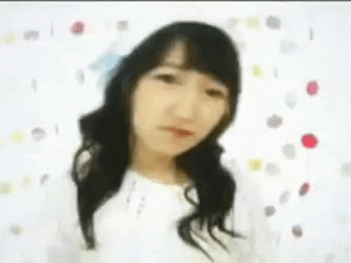 a woman with long hair is standing in front of a white wall with polka dots .
