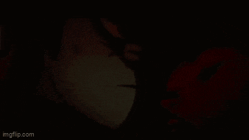 a man and two women are kissing in a dark room in a cartoon .