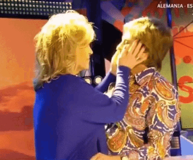 a woman is touching another woman 's face with the word alemania on the bottom