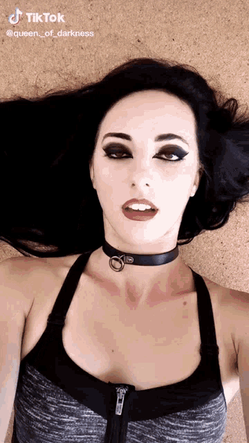 a woman wearing a choker and a gray tank top with tiktok written on the bottom right