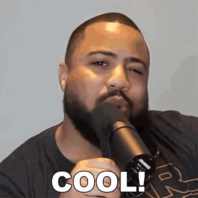 a man with a beard is holding a microphone with the word cool written on it