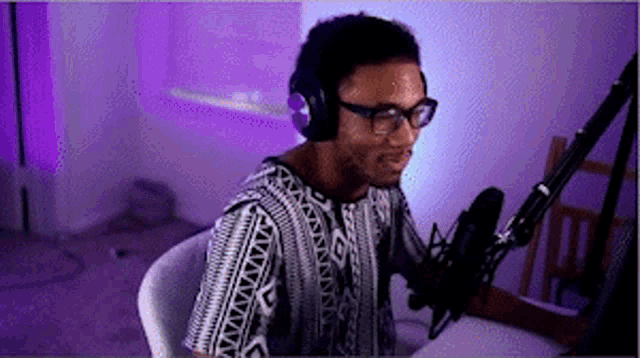 a man wearing headphones and glasses sitting in front of a microphone