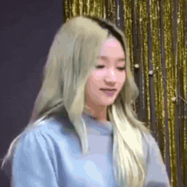 a woman with blonde hair is wearing a blue sweater and looking at the camera .