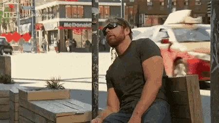 a man is sitting on a bench in front of a mcdonald 's .