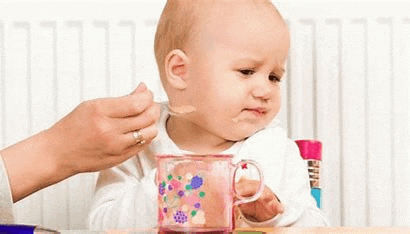 a woman is feeding a baby with a spoon .